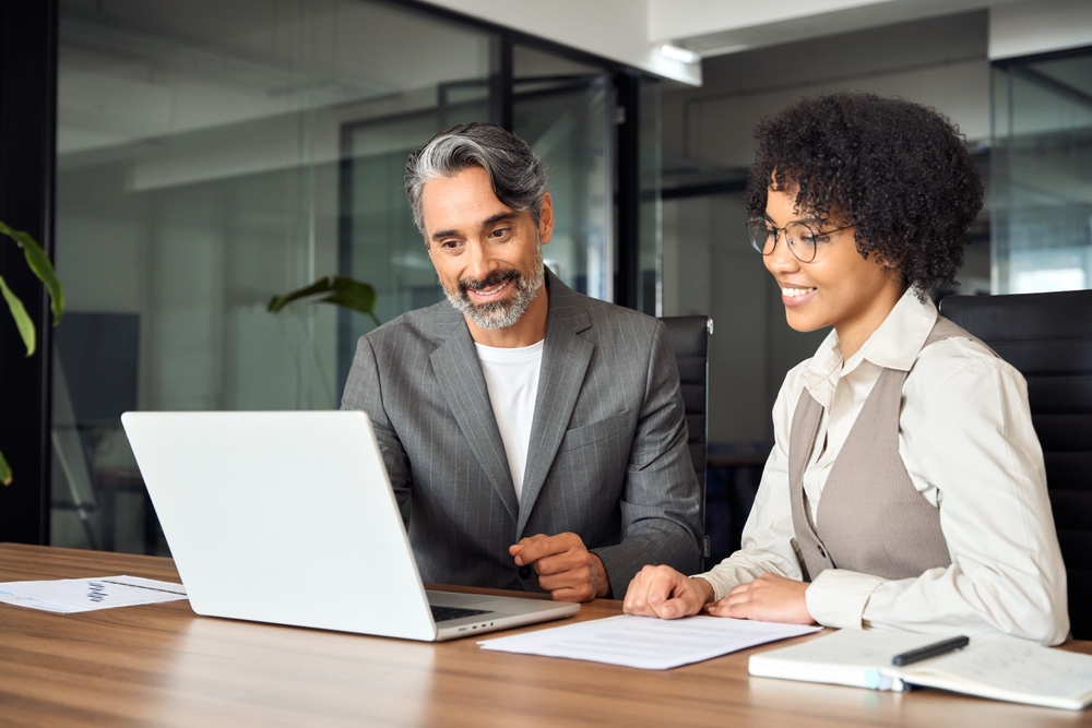 financial accountant and client looking at a laptop together. both people are smiling.